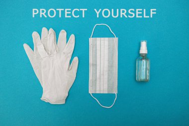 Tıbbi maske, eldivenler, mavi arka planda alkol dezenfektanı ve PROTECT kendin. Kavram, kavga, önleme, koronavirüs gribi enfeksiyonuna karşı karantina. Yukarıdan görüntüle