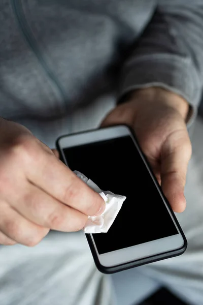 Man cleaning smartphone screen with alcohol or disinfectant. The concept of cleaning a dirty phone screen to prevent diseases from infectious bacteria. coronavirus covid 19.