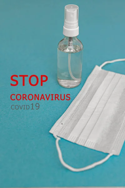 Ochronna maska medyczna, dezynfektor alkoholu na niebieskim tle. tekst STOP CORONAVIRUS. Koncepcja, walka, profilaktyka, kwarantanna przeciwko zakażeniu wirusem koronawirusa. — Zdjęcie stockowe