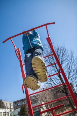Ukrayna 'nın Kiev kentindeki bir çocuk parkında, çok katlı bir binanın bahçesinde, sonbaharda mavi ceket ve kot pantolon giyen bir çocuk oynuyor. Seçici odaklanma, perspektif