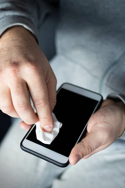 Man cleaning smartphone screen with alcohol or disinfectant. The concept of cleaning a dirty phone screen to prevent diseases from infectious bacteria. coronavirus covid 19.