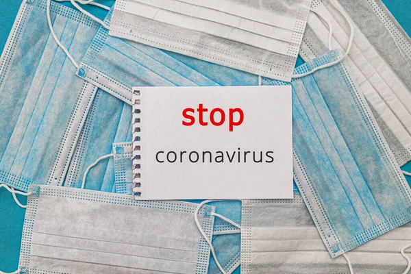 Medische wegwerp gezichtsmaskers op een blauwe achtergrond met de inscriptie stop coronavirus covid 19. Wereldpandemie coronavirus. Stop de pandemie. Gezondheid en preventie van influenza en een besmettelijke ziekte — Stockfoto