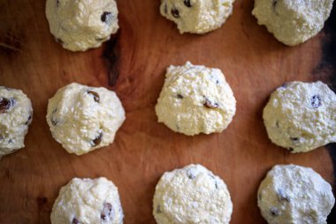 Tahtada Rus geleneksel ev yapımı, kuru üzümlü süzme peynirli gözlemeler için hazır. Tahta bir masada peynirli kekler.
