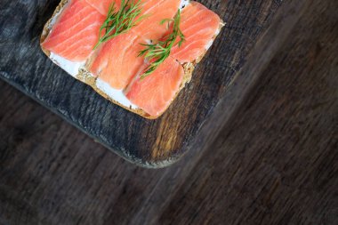 Krem peynirli tam tahıllı tost ve az tuzlu somon ve koyu ahşap bir tahtanın üzerinde dereotlu dereotu. Düz yatıyordu. Uzayı kopyala Kavram, sağlıklı kahvaltı, yemek, atıştırmalık..