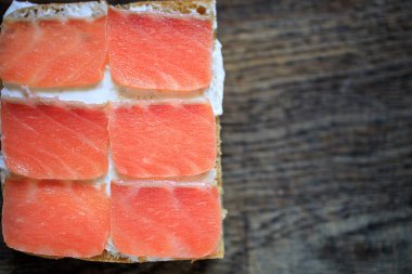 Krem peynirli tam tahıllı tost ve koyu ahşap bir tahtanın üzerinde hafif tuzlu somon. Düz yatıyordu. Uzayı kopyala Kavram, sağlıklı kahvaltı, yemek, atıştırmalık..