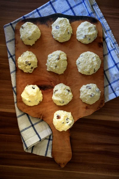 Sul bordo preparato per friggere frittelle di fiocchi di latte fatte in casa tradizionali russe con uva passa - le torte di formaggio su un tavolo di legno — Foto Stock