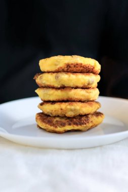 Masanın üzerinde keten rengi parlak bir masa örtüsü, ekşi krema soslu beyaz bir sos, tabakta peynirli krep, çatal, beyaz bir masa örtüsü üzerinde bıçak var. Kavram, basit sağlıklı