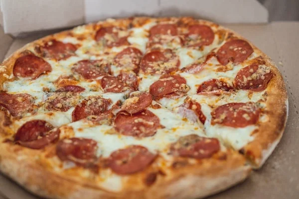 Pizza aux pepperoni hachés en morceaux dans une boîte de courtoisie. Concentration sélective. Vue d'en haut — Photo