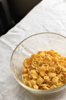 Açık kırsal masa örtüsü üzerinde şeffaf cam bir tabakta mısır gevreği. Boşluğu kopyala.