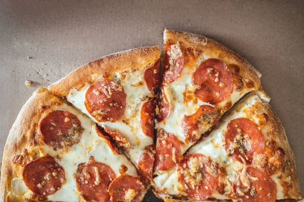Pizza aux pepperoni hachés en morceaux dans une boîte de courtoisie. Concentration sélective. Vue d'en haut — Photo
