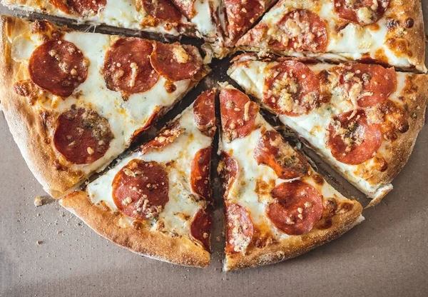 Pizza com pepperoni cortado em pedaços em uma caixa de cortesia. Foco seletivo. Vista de cima — Fotografia de Stock