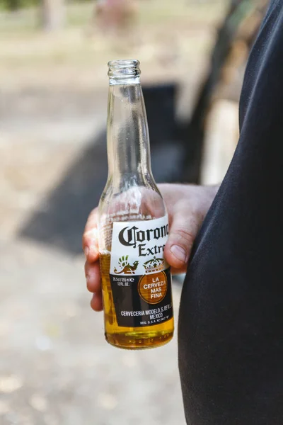 Een fles Corona bier in mannelijke handen op de achtergrond van een grote bierbuik. Kiev, Oekraïne. — Stockfoto