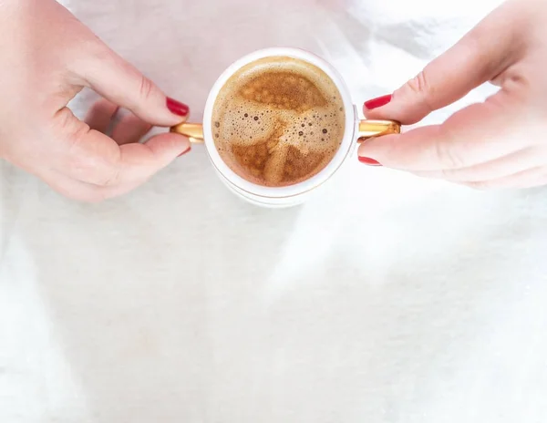 Manos femeninas recortadas con manicura roja sostienen un mandril con café capuchino sobre un fondo descuidado retro blanco claro. Copiar espacio. Piso tendido, vista superior . —  Fotos de Stock