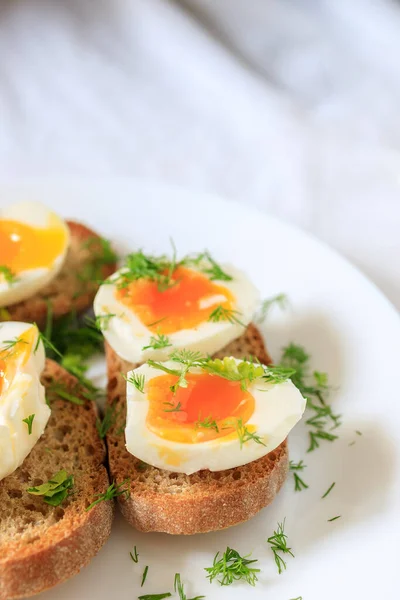 Metades de ovo macio-fervidas com endro em pão de grão inteiro torrado em uma chapa branca. Close-up, vista superior. Conceito de pequeno-almoço saudável, saudável e saudável . — Fotografia de Stock