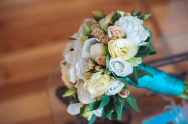 Düğün bir odada cam masa üzerinde mavi bir kurdele ile beyaz gül buketi