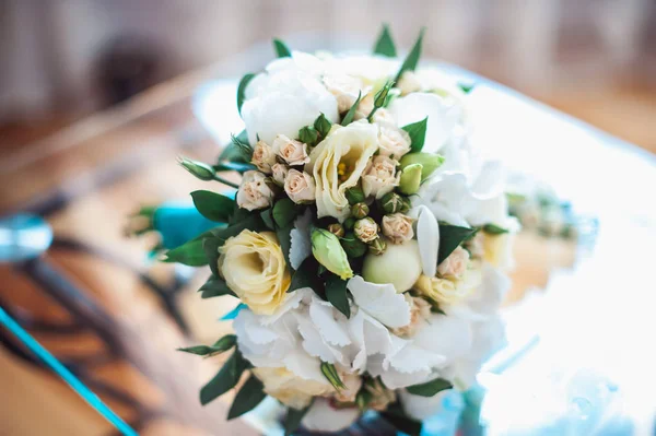 Buquê de casamento de rosas brancas com uma fita azul na mesa de vidro em uma sala — Fotografia de Stock