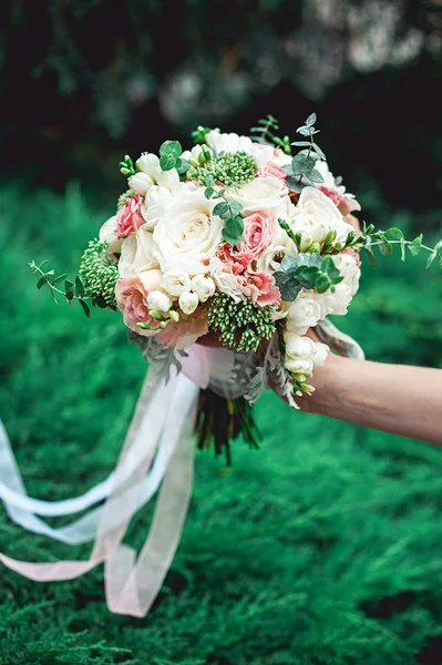 Noiva segurando um buquê de casamento feito de rosas — Fotografia de Stock