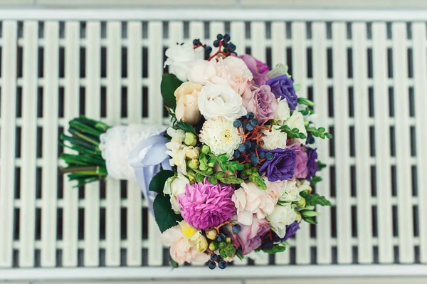Ramo de novia de diferentes flores envueltas cinta de encaje en una rejilla blanca — Foto de Stock