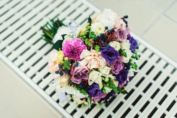 Buquê de noiva de diferentes flores envolto fita de renda em uma grade branca — Fotografia de Stock