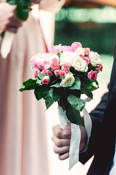 Verloofde in een donker blauwe pak houdt een bruiloft boeket gemaakt van rozen — Stockfoto