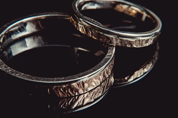 Anillos de boda martillados sobre fondo negro. macro — Foto de Stock