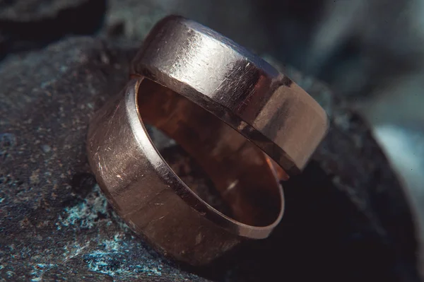 Dvě široké zlaté snubní prsteny se poškrábal na kamenný povrch — Stock fotografie