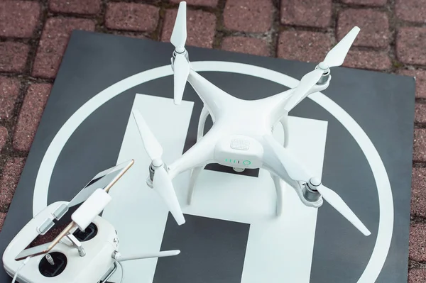 Remote controller and quad copter on the helicopter landing spot — Stock Photo, Image