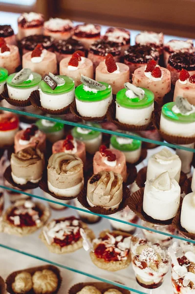 Rows of italian mignon cakes on a glass stand — Stock Photo, Image