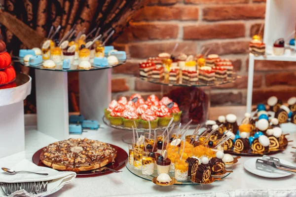 Düğün candybar yaldızlı kağıda mavi beyaz sweets. Bir arka plan üzerinde tuğla duvar