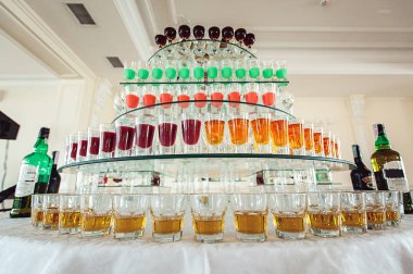 Satır bir cam stand ayakta küçük bardaklarda renkli yeşil sarı ve kırmızı alkol çekim çeşitli