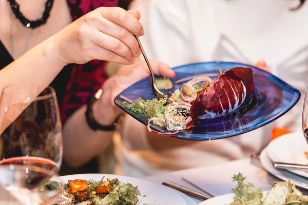 Женщина в ресторане кладет салат в миску — стоковое фото