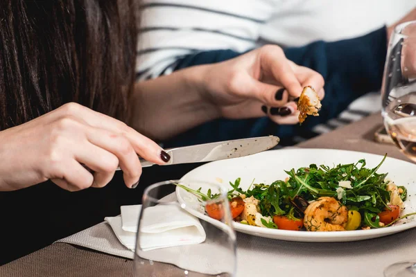 Женщина ест вкусный салат с креветками в ресторане — стоковое фото