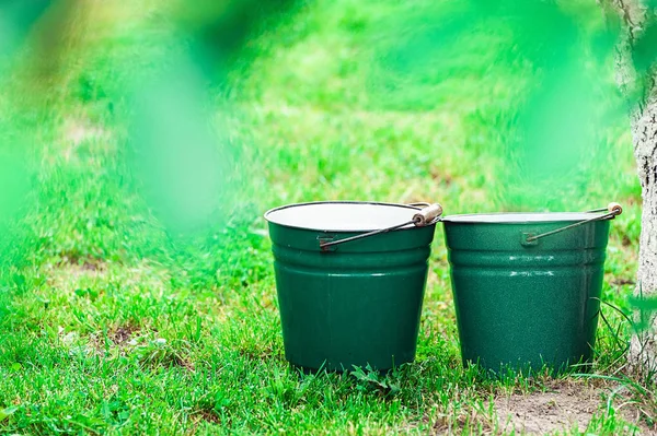 two green metal bucket on the rass field.