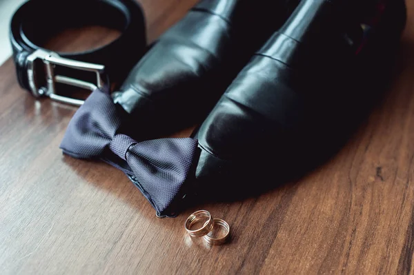 Черный галстук-бабочка лежит перед кожаными туфлями и ремнем. Свадебное утро — стоковое фото