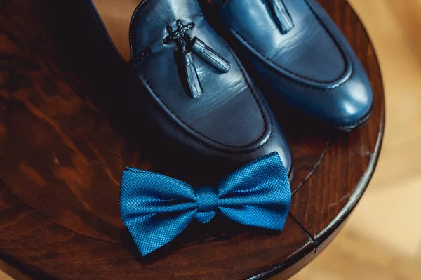 Blaue Schuhe und Fliege auf einem hölzernen runden Hocker. Accessoire für formelle Kleidung. Symbol für Eleganz und Mode für Männer. — Stockfoto
