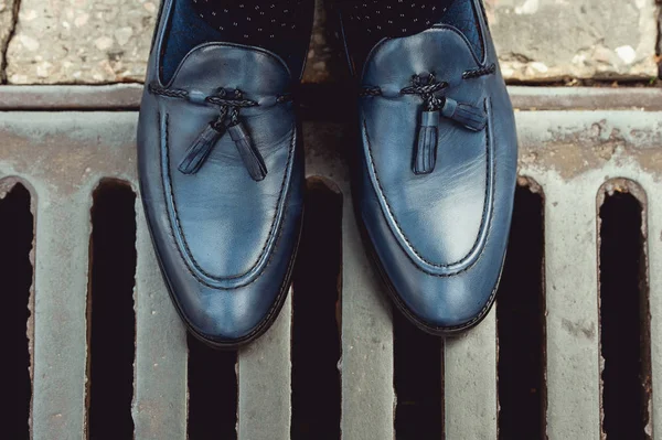 Zapatos de hombre azules en una rejilla de aguas residuales de metal — Foto de Stock