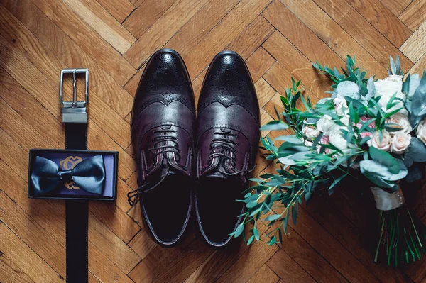 Κοντινό πλάνο, αξεσουάρ, ο σύγχρονος άνθρωπος. Μαύρο παπιγιόν, δερμάτινα παπούτσια, ζώνη και γαμήλια ανθοδέσμη σε ξύλινα ρουστίκ φόντο. Για το επίσημο ύφος του φορώντας — Φωτογραφία Αρχείου