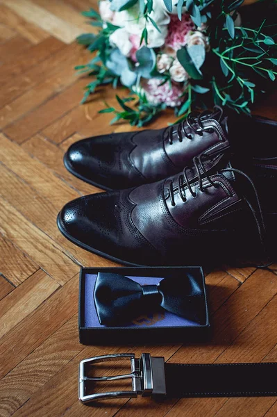 Nahaufnahme der Accessoires des modernen Menschen. schwarze Fliege, Lederschuhe, Gürtel und Brautstrauß auf rustikalem Holz-Hintergrund. Set für den formalen Tragestil — Stockfoto