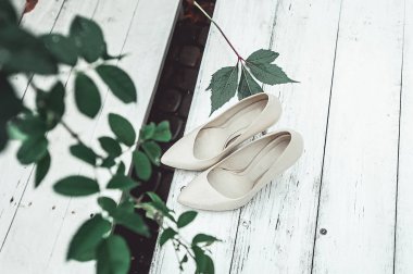 Beyaz ahşap bir masa üzerinde yağmurda beyaz düğün ayakkabıları