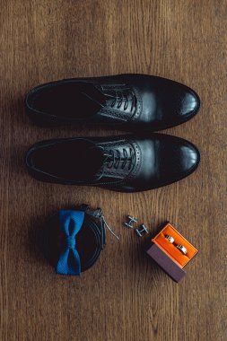 Modern insan aksesuarları, yakın çekim. Mavi papyon, deri ayakkabı, kemer, kol düğmesi ve bir turuncu kutu nikah yüzükleri