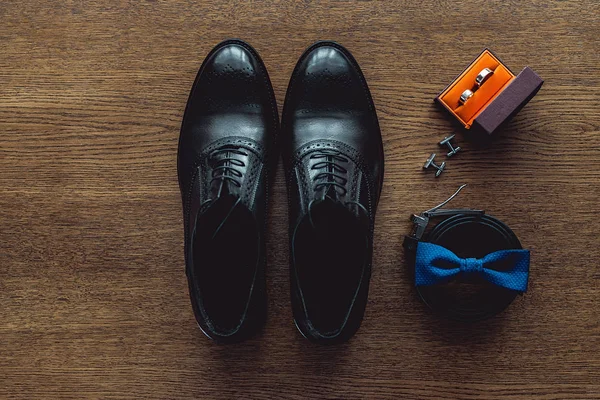 Close up of modern man accessories. Blue bowtie, leather shoes, belt, cufflinks and wedding rings in a orange box