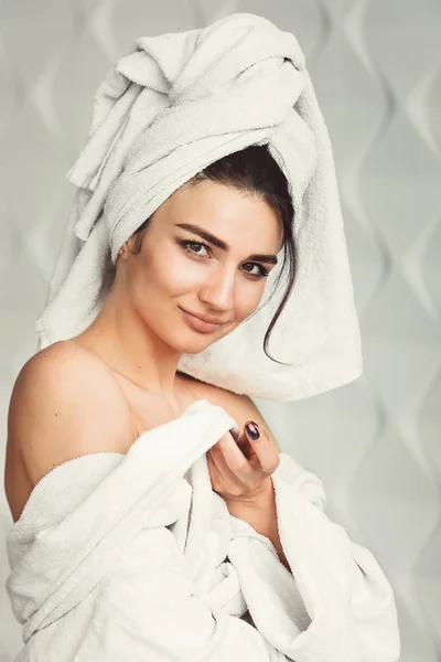 Sexig ung flicka med mörkt hår, stora ögon och mörka ögonbryn bär vit badhandduk robe whith på hennes huvud. — Stockfoto