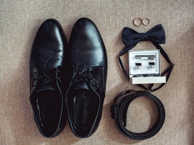 Modern insan aksesuarları, yakın çekim. Alyans, siyah papyon, deri ayakkabı, kemer ve kol düğmeleri