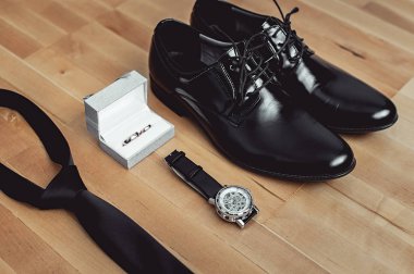 Modern damat aksesuarları, yakın çekim. Alyans, siyah kravat, deri ayakkabı ve izle