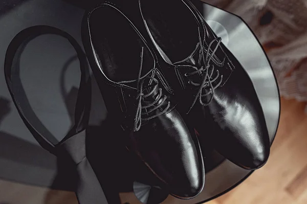 Κοντινό πλάνο, αξεσουάρ, ο σύγχρονος άνθρωπος. μαύρη γραβάτα και δερμάτινα παπούτσια στο τραπέζι μαύρο γυαλί — Φωτογραφία Αρχείου