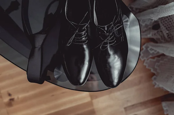 Närbild av moderna människan tillbehör. svart halsduk och läderskor på svart glasbord — Stockfoto