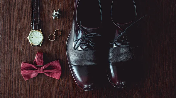 Close up of modern man accessories. wedding rings, cherry bowtie, leather shoes, watch and cufflinks