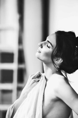 Önce penceresini ayakta ve banyodan sonra havlu ile çıplak vücudu kapsayan gündoğumu hayran seksi genç esmer kadın.