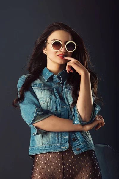 Ursnygg flicka med rött läppstift och vita solglasögon klädd i en blå jacka röda högklackade skor och genomskinliga tights utan trosor — Stockfoto