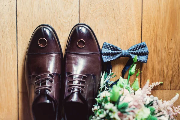 blue bow tie, leather shoes and wedding rings. Grooms wedding morning. Close up of modern man accessories